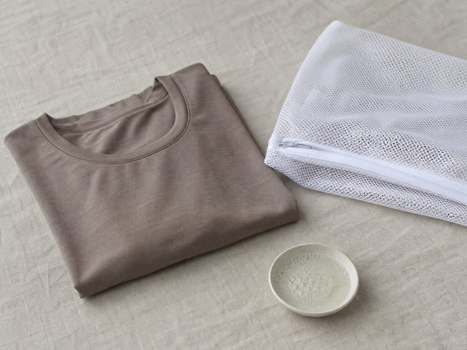 A folded lambswool jumper beside wool detergent flakes and a garment brush