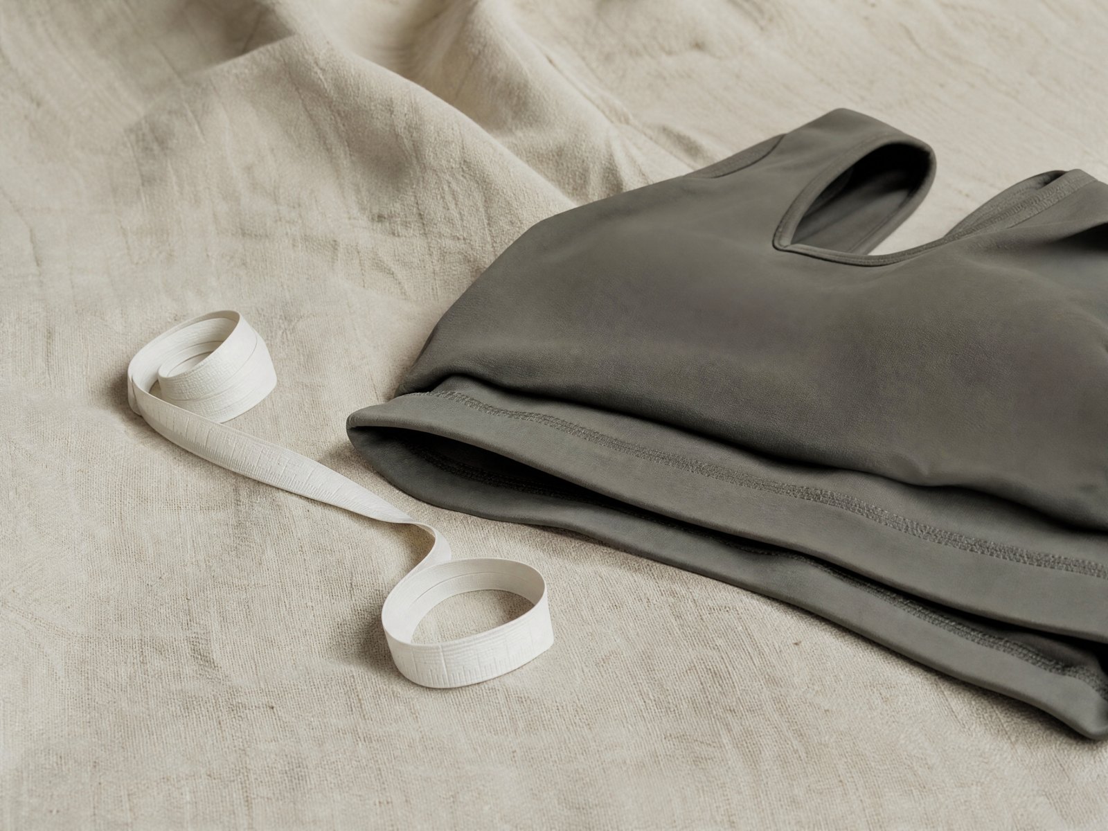 A folded ribbed knitted sock beside an uncoiled cloth tape measure